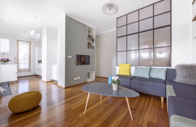 Kuchyň s obývacím pokojem propojuje jednolitý dřevěný dekor podlahy. Prostor zjemňují odstíny zelenkavé tapety a výmalba v nejsvětlejším barevném tónu tapety a stejně tak decentní barevné odstíny sedacího nábytku a konferenčního stolku