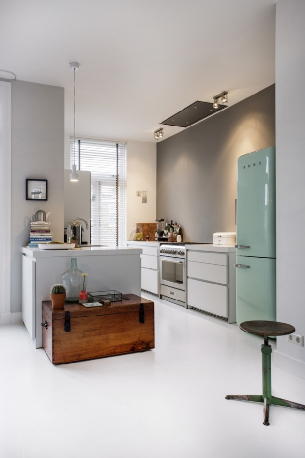 KUCHYŇ Bílá neutrální kuchyň v moderním stylu nechává vyniknout barevné retro lednici a staré dřevěné truhle