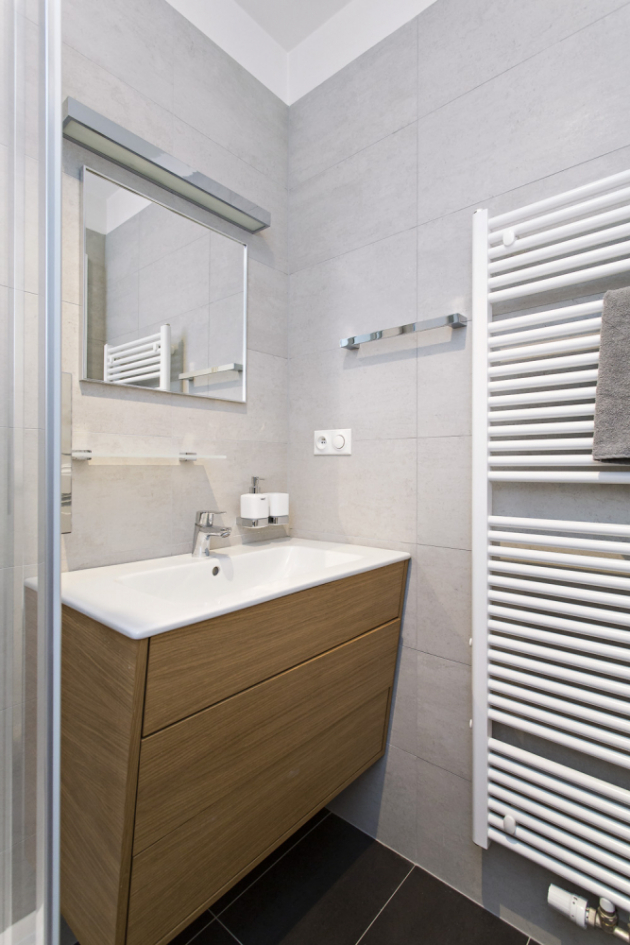 KOUPELNA Sprchový kout a umyvadlo posazené na zešikmené umyvadlové skříňce je dostatečný komfort, který potřebuje zaměstnaný muž v příležitostném bydlení 