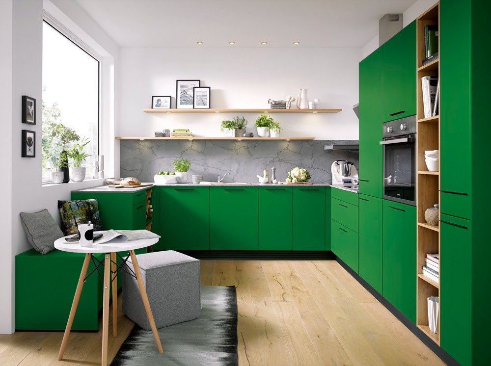 Výrazný odstín zelené barvy kuchyně z řady C (Schüller) tlumí dekor světlého dřeva v policích a na podlaze