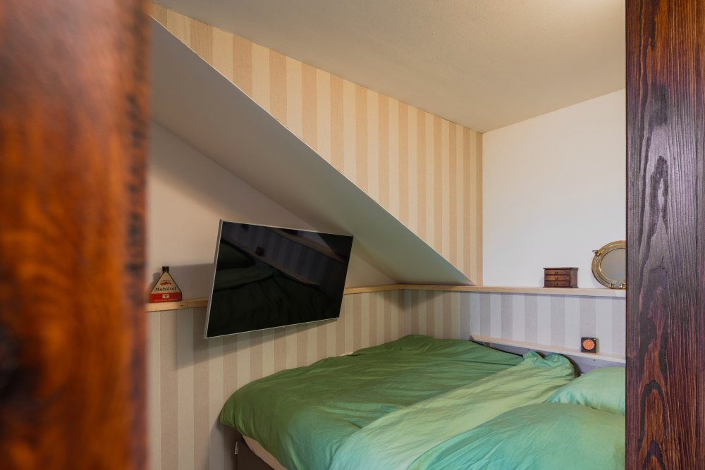 Jedna ložnice je vytapetovaná v krémové barvě v kombinaci obložení světlého dřeva. 