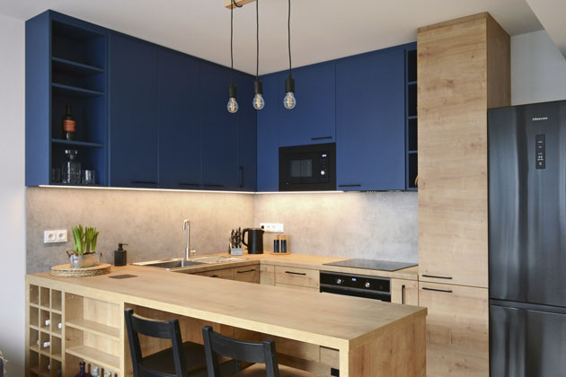 Kuchyňská sestava působí díky kombinaci dekoru světlého dřeva se sytě modře lakovanou horní skříňkou originálně