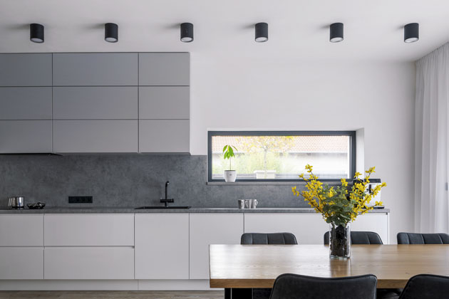 Minimalistický styl kuchyně umocňují bezúchytková dvířka, horizontální a vertikální členění plochy a decentní kombinace šedých odstínů