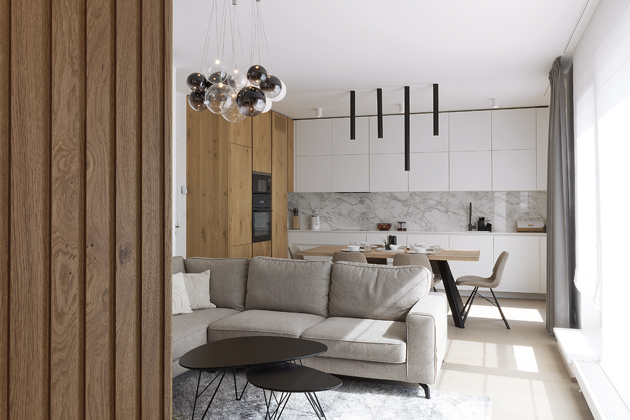 V obývací části je nepřehlédnutelný italský lustr připomínající bublinky. Jedním z přání majitelů byla rohová pohovka, tato konkrétní v barvě taupé je spolu s černými konferenčními stolky od Lino Design