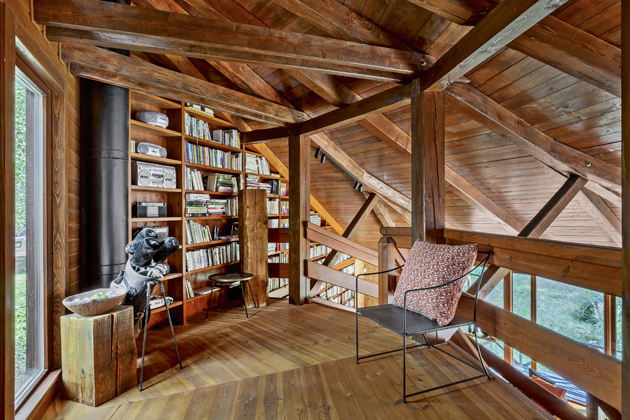 Knihovna sahající z přízemí až na galerii vytváří v dřevěném interiéru osvěžující barevnou kulisu