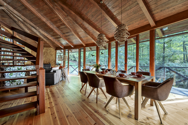 Díky prosklené stěně se můžete celoročně kochat výhledem na zahradu a les. Okna sem také vnášejí denní světlo, kterého kvůli netypické konstrukci domu není v interiéru mnoho