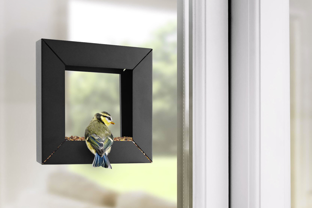 Ocelové krmítko pro ptáky Frame lze snadno připevnit na okno i na dřevo. Krmivo pak stačí dávkovat do spodní části rámu, cena 1 170 Kč