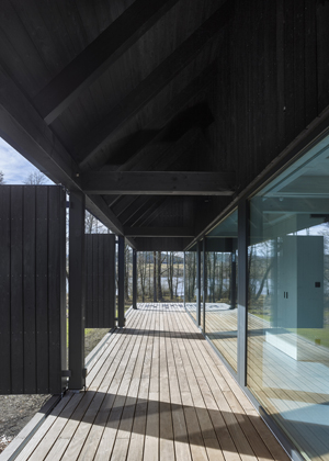 Dřevostavba je založena na kamenn&eacute; platformě, kter&aacute; ji ze třech stran lemuje a vytv&aacute;ř&iacute; krytou i nekrytou terasu. Na pochoz&iacute; terasu architekti použili tropick&eacute; dřevo, jež d&eacute;le vydrž&iacute; a je tvarově st&aacute;lej&scaron;&iacute;